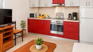 Una cocina compacta con armarios rojos, un microondas, una cafetera y un tostador.