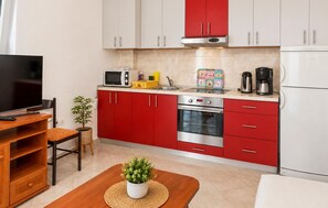 Eine kleine Küche mit roten Schränken, einer Mikrowelle, einer Kaffeemaschine und einem Toaster.