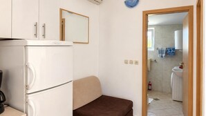 Una cocina compacta con refrigerador, un sofá y un espejo.