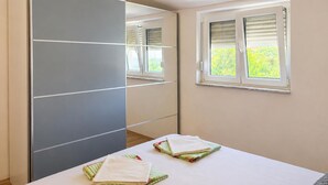 Un dormitorio con cama, espejo y ventana con persianas.