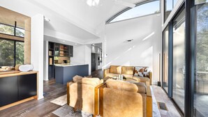 A modern interior with a sofa set, a kitchen area, and large windows.
