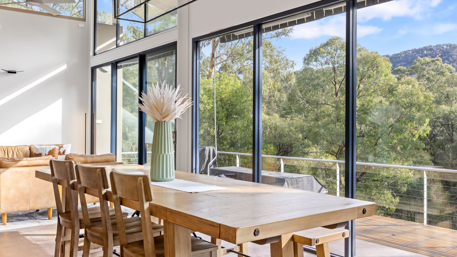 Un intérieur moderne comprenant un coin repas, de grandes fenêtres et une vue sur un paysage boisé.