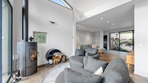 A modern living room with a fireplace, grey sofas, and a large window.