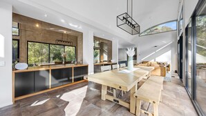 A modern kitchen with a large island, dark cabinetry, and a dining area with a wooden table and benches.