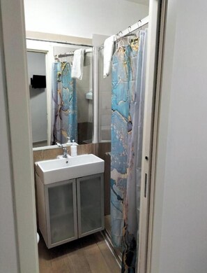 Ein Badezimmer mit Duschvorhang, Waschbecken und Spiegel.