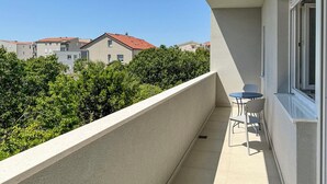 Un balcón con mesa y sillas, vistas a edificios vecinos y un cielo despejado.
