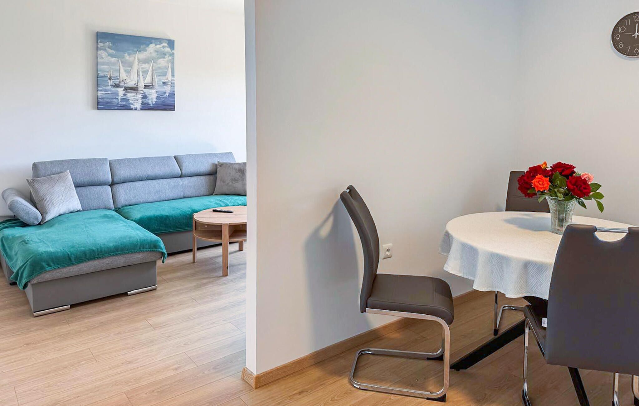 Ein modernes Wohnzimmer mit einer Couch, einem Couchtisch, einem Esstisch mit Stühlen und einem Bild an der Wand.