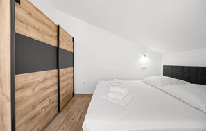 Ein Schlafzimmer mit einem Bett, weißen Leinentüchern, einem Holzschrank und einem Kopfteil.