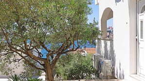 Un bâtiment doté d’une porte en arc de cercle, de climatiseurs installés à l’extérieur et d’un arbre au premier plan.