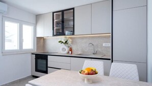 Una cocina moderna con lavavajillas integrado, un lavamanos y una zona de comedor con mesa y sillas.