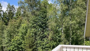 A white balcony railing with a view of dense green trees and pink flowers. - 4 Star Holiday Home in Hindas (Hindas)
