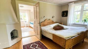 A bedroom with a wooden bed, a patterned rug, a radiator, and a window with a view of greenery.