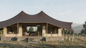 A tent-like structure with a covered patio area, stone steps, and a view of mountains. - VICTORIA STARFALL MAASAI MARA (Maasai Mara)