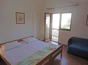 A bedroom with a bed, a blue sofa, a balcony with a railing, and a door leading outside. - Villa Matan (Murter-Kornati)