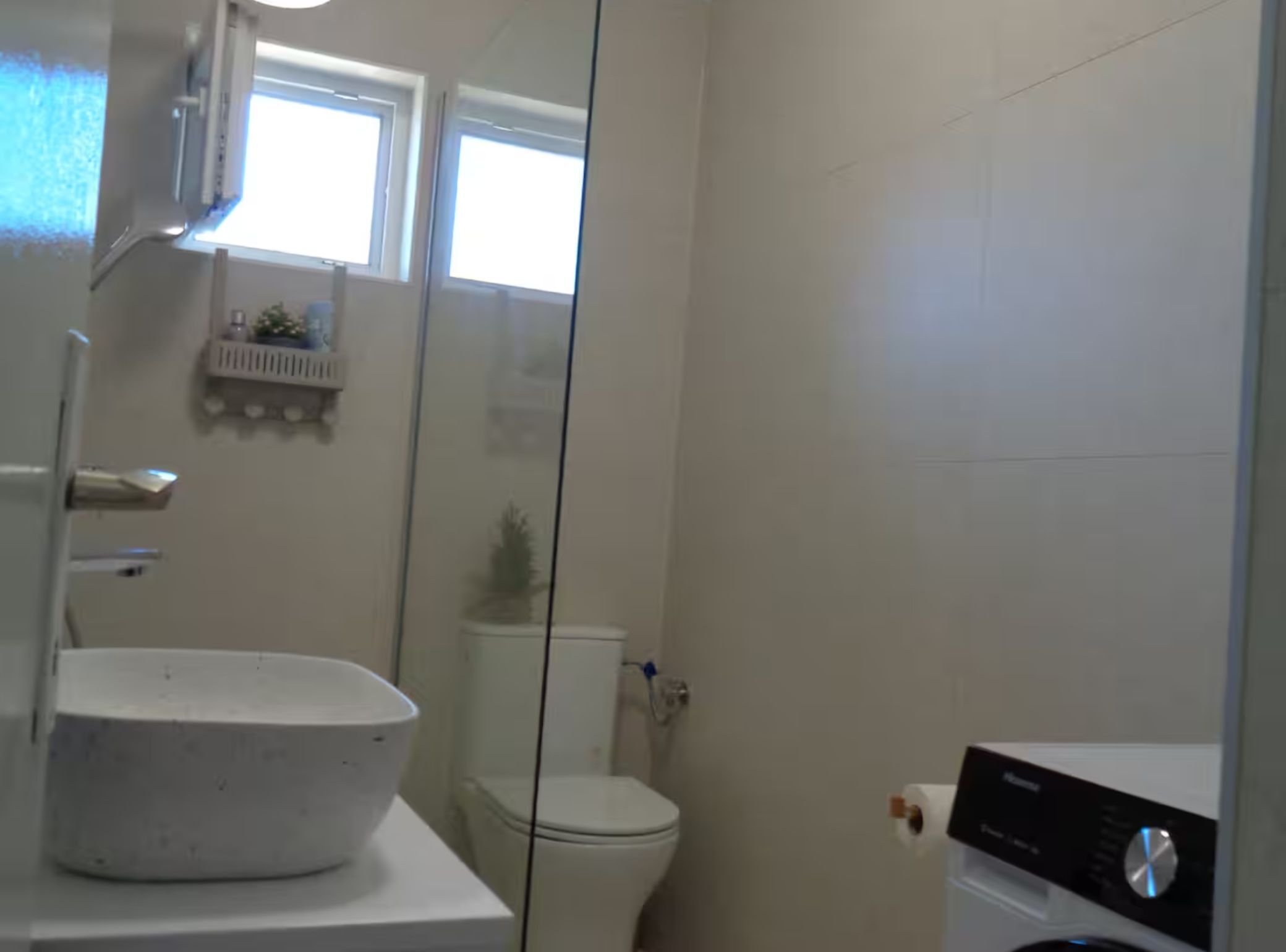 A bathroom with a white sink, toilet, and a washing machine.