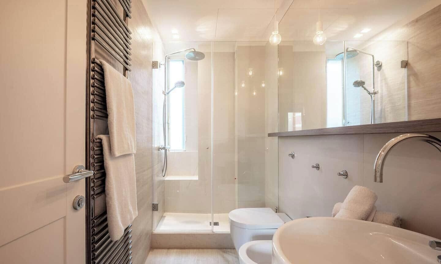 Ein modernes Badezimmer mit einer gläsernen Duschkabine, einer separaten Toilette und einer freistehenden Badewanne.