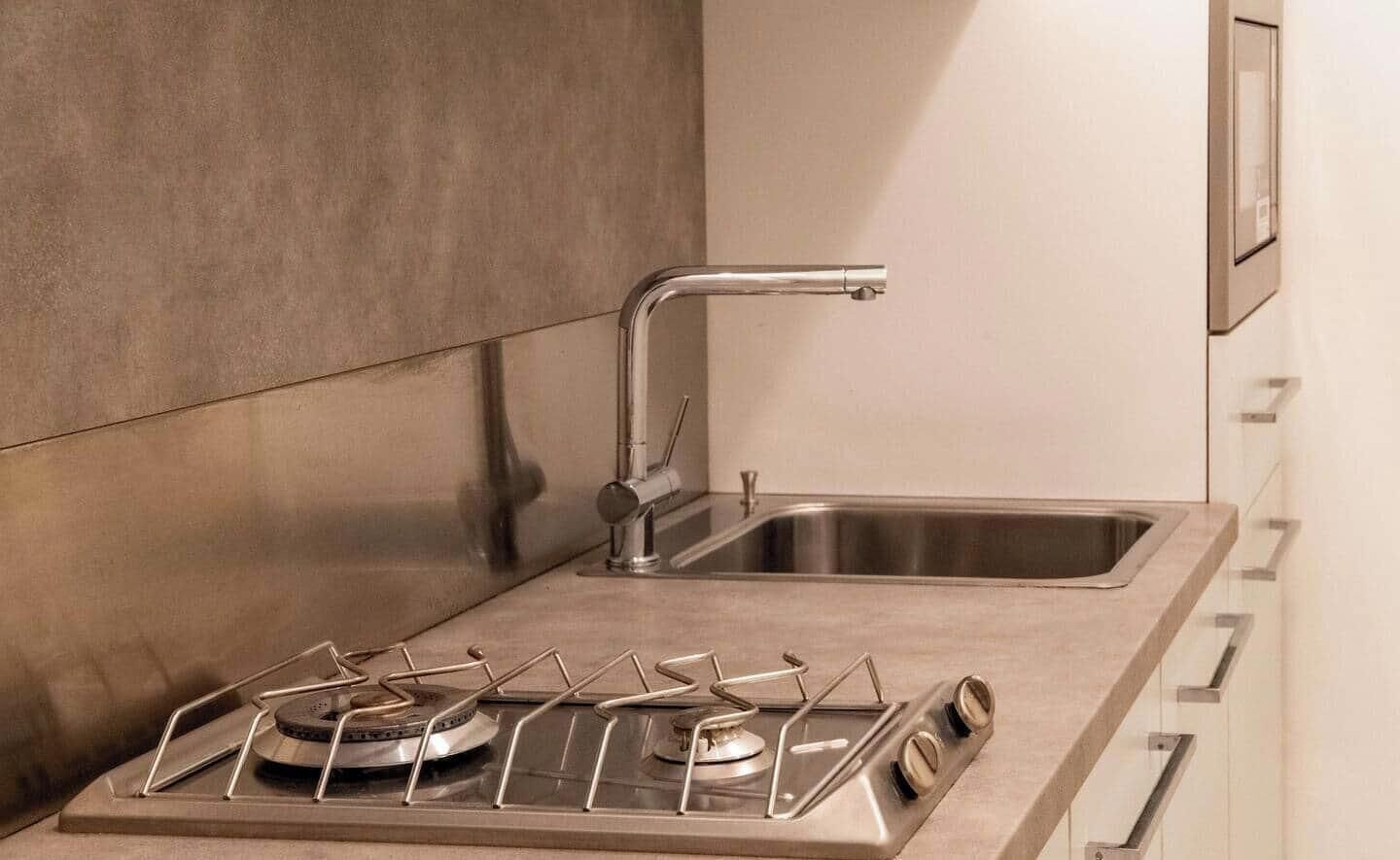 A kitchen with a stainless steel sink, a gas stove with four burners, and a modern faucet.