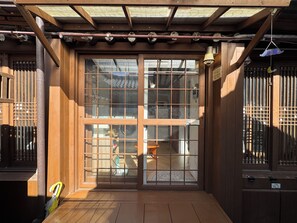 A wooden structure with a large sliding glass door, a wooden bench, and a hanging bell. - 경복궁역 도보 2분 거리_ 한옥 몽유(夢遊)-별채 단독 사용, 대형 편백욕조,Netflix (Seoul)