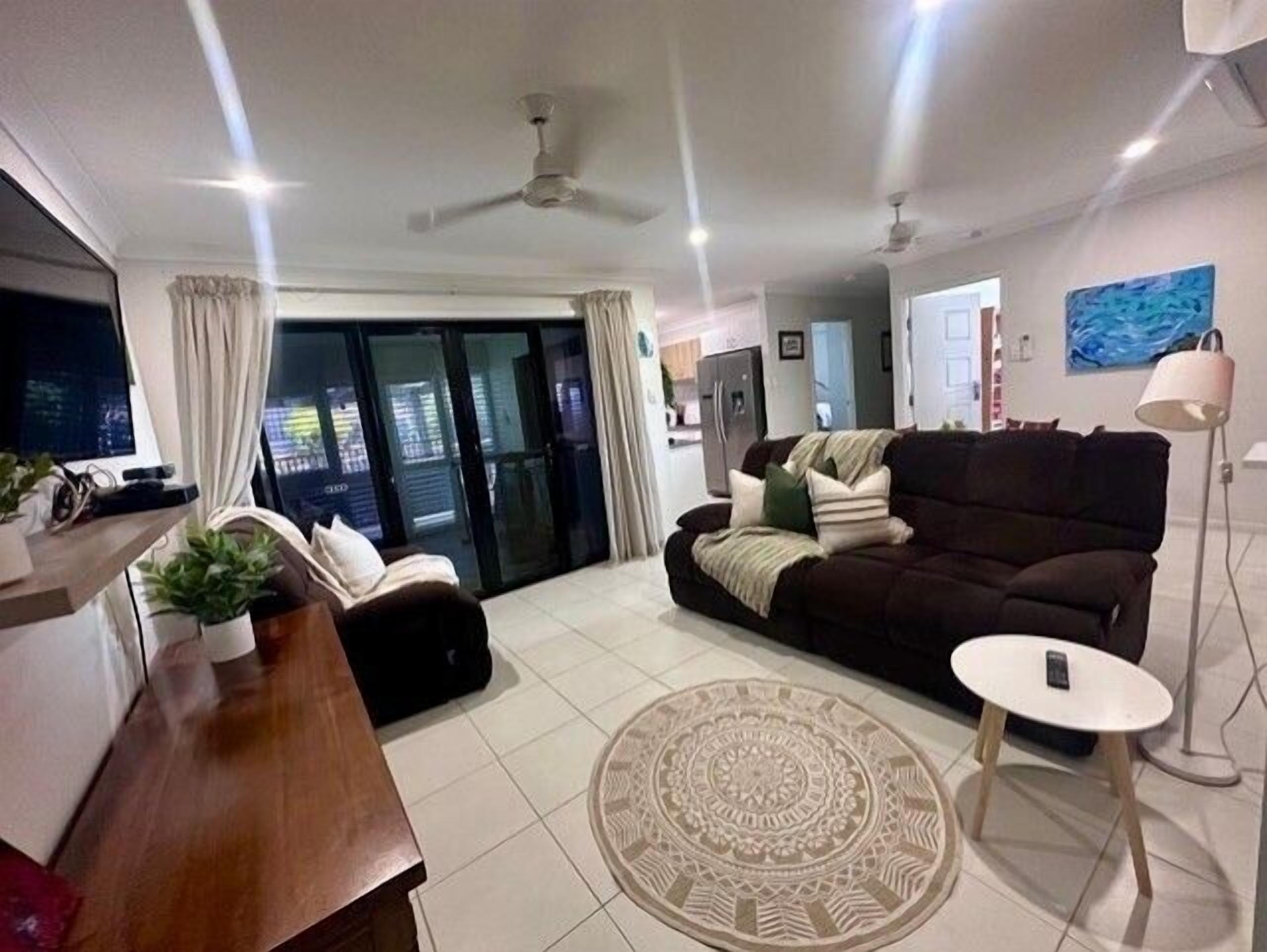 A modern living room with a sofa, a coffee table, a TV, and a dining area.