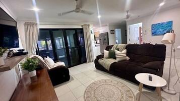 A modern living room with a sofa, a coffee table, a TV, and a dining area.