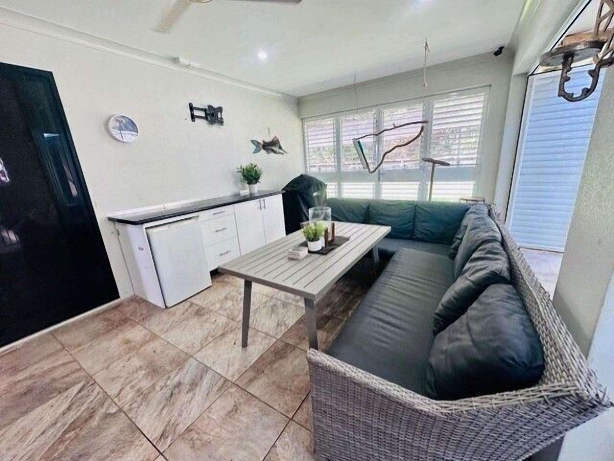 A compact living space with a kitchenette, a dining table, a sofa, and a small refrigerator.