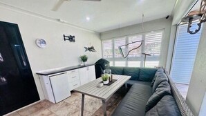 Un espacio habitable compacto con kitchenette, una mesa de comedor, un sofá y un refrigerador pequeño.