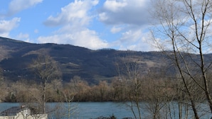 A landscape with a body of water, trees, and hills in the background.