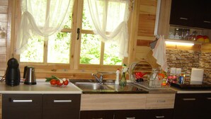 A kitchen with wooden cabinets, a sink, a coffee maker, and a window with curtains.