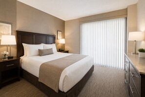A hotel room with a large bed, two bedside tables with lamps, a dresser, and a window with blinds. - Stylish 1BR Urban Retreat with Skyline Views in Downtown Toronto! (Toronto)