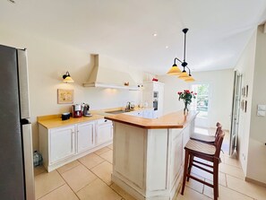 A modern kitchen with white cabinetry, a wooden island, and pendant lighting.