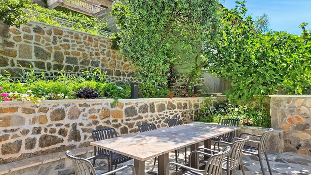 Une terrasse extérieure avec un mur en pierre, une table et des chaises.