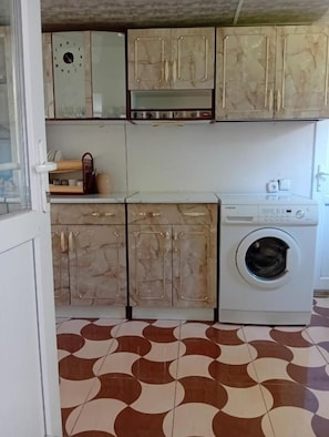 A kitchen with a washing machine, cabinets, and a patterned floor.