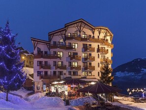 A multi-story hotel with balconies, a restaurant, and outdoor seating. - Cozy apartment in La Tania center, 4 pers, ski-in/ski-out (La Tania)