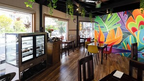 Interior de restaurante con suelo de madera, vitrina de cristal y un mural colorido en la pared.