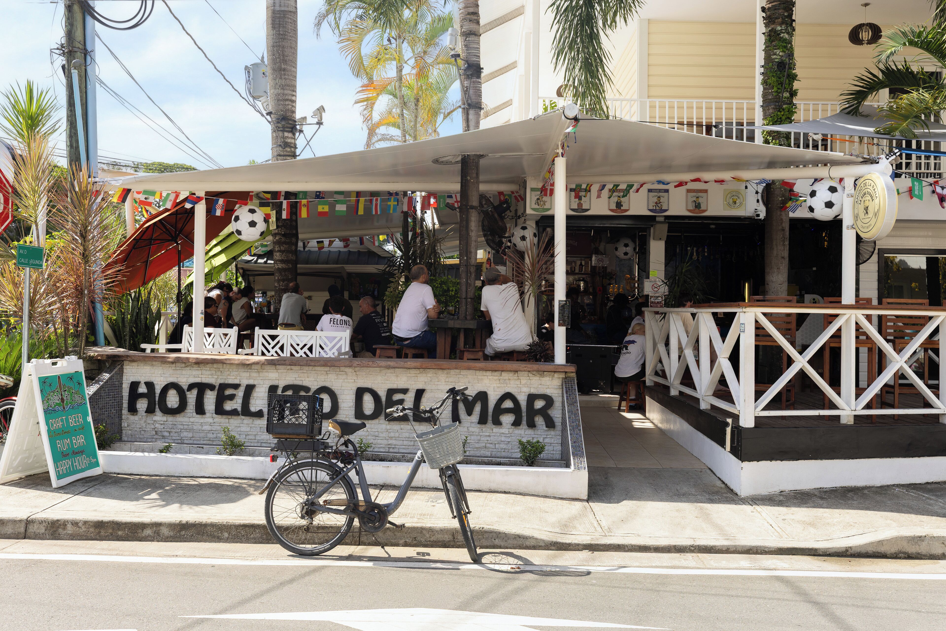 Ein Hotel namens 'HOTEL DEL MAR' mit einer Schautafel, einem Fahrrad vor der Tür und Blick auf die Straße.