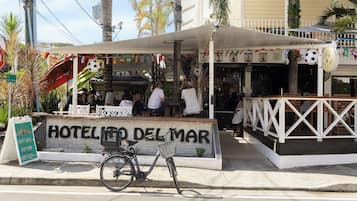 Ein Hotel namens 'HOTEL DEL MAR' mit einer Schautafel, einem Fahrrad vor der Tür und Blick auf die Straße.
