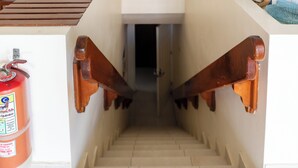 Una escalera con barandas de madera y un extintor en la pared a la izquierda.