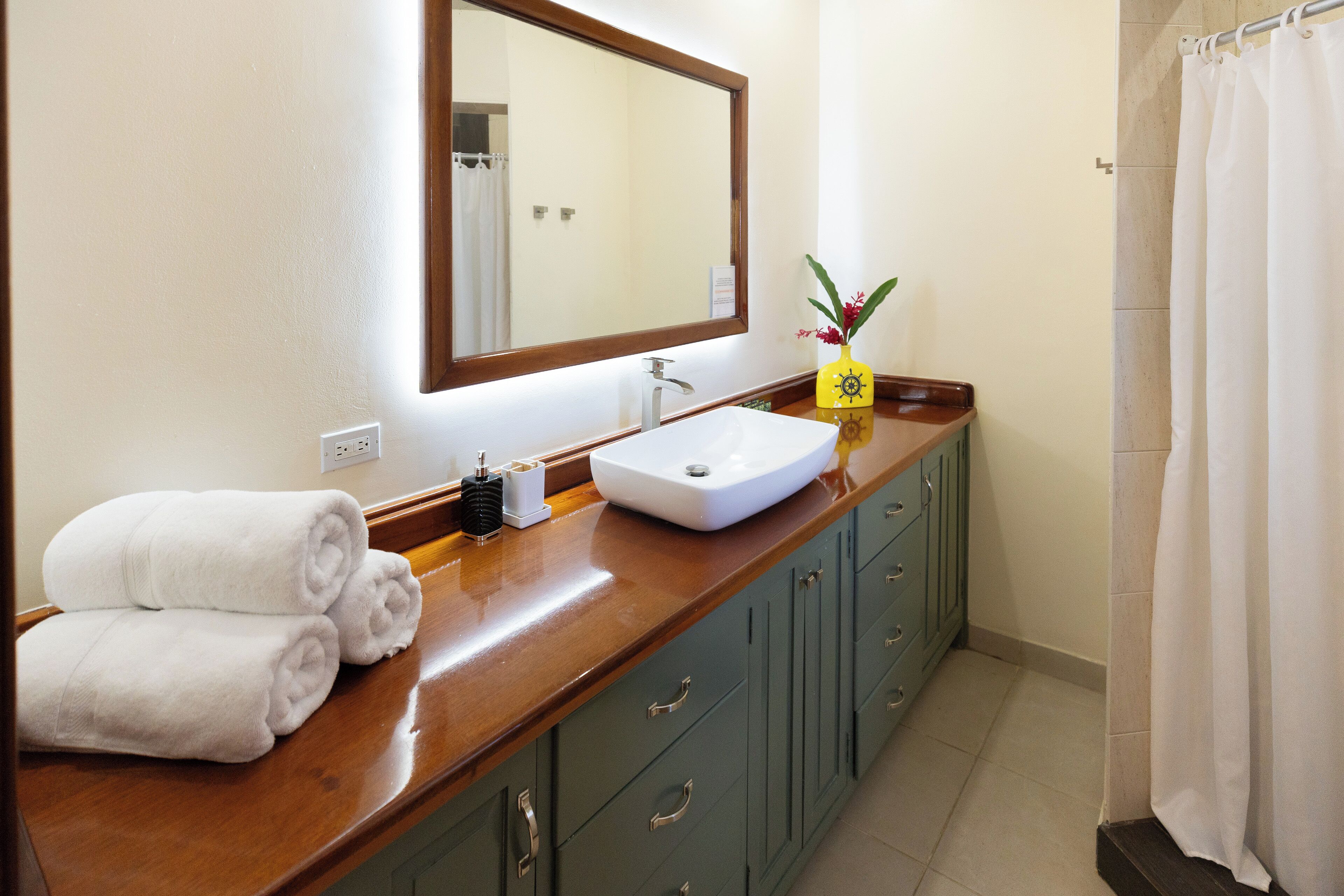 A bathroom with a wooden vanity, a white sink, a mirror, and a towel rack.