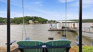 Una silla colgante con vista a un lago, con un muelle y edificios al fondo.