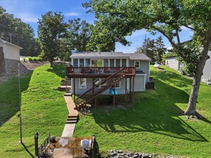 Ein zweistöckiges Haus mit einer Terrasse, einer Treppe und einem kleinen Außenbereich mit Wasserspiel.