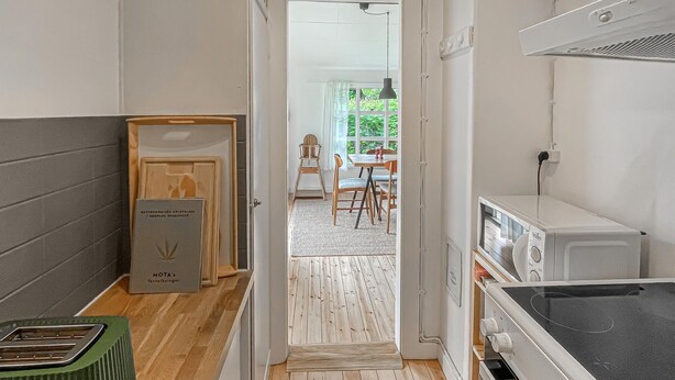 A narrow hallway with a wooden floor, a microwave, and a green trash bin. - 2 bedroom stunning home in Rørvig (Rørvig)