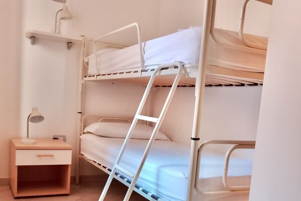 Un lit superposé avec une échelle, une table de chevet et une lampe.