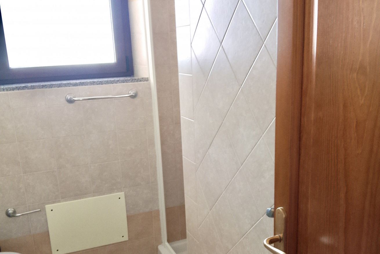 A bathroom with a window, a towel rack, and a door.