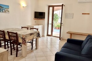 Zona pranzo con tavolo e sedie, televisore e divano.