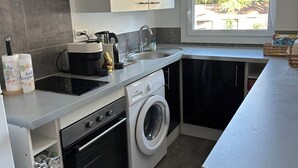 Een kleine keuken met een wasmachine, fornuis en spoelbak.