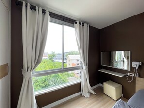 A bedroom with a large window, a bedside table, a mirror, and a TV. - Room71atchangwattana (Pak Kret)