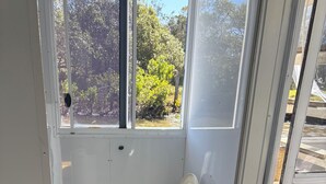 Un baño pequeño y cerrado con inodoro, una ventana y un balde.