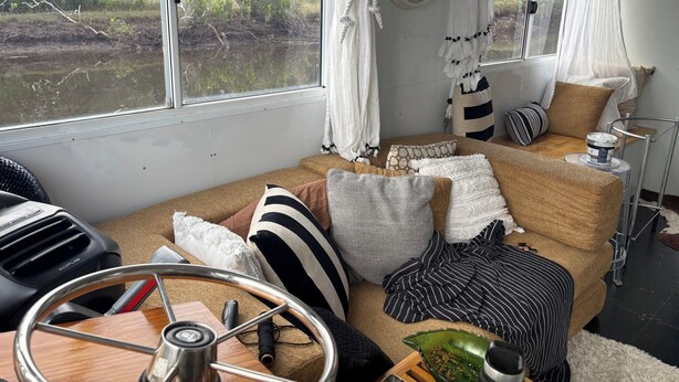 Una habitación acogedora con un ventanal grande, un reloj y una variedad de cojines y almohadas en un sofá.