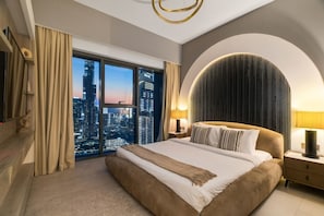 A hotel room with a large bed, a city view, a curved wall, and a modern chandelier. - 3BR Burj Khalifa View Pool & Gym (Kabupaten Buleleng)