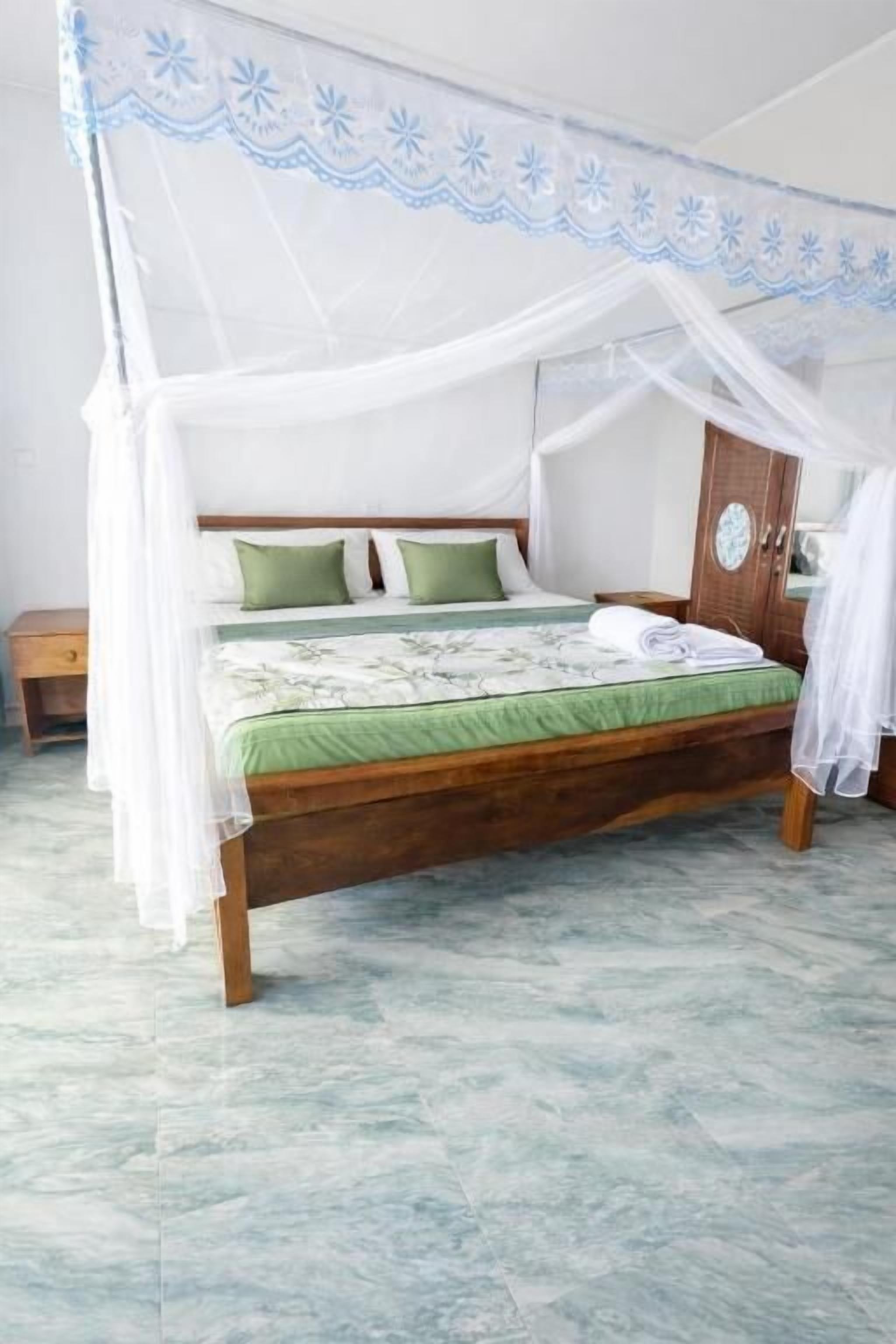 A bed with a canopy, green pillows, and a wooden headboard.